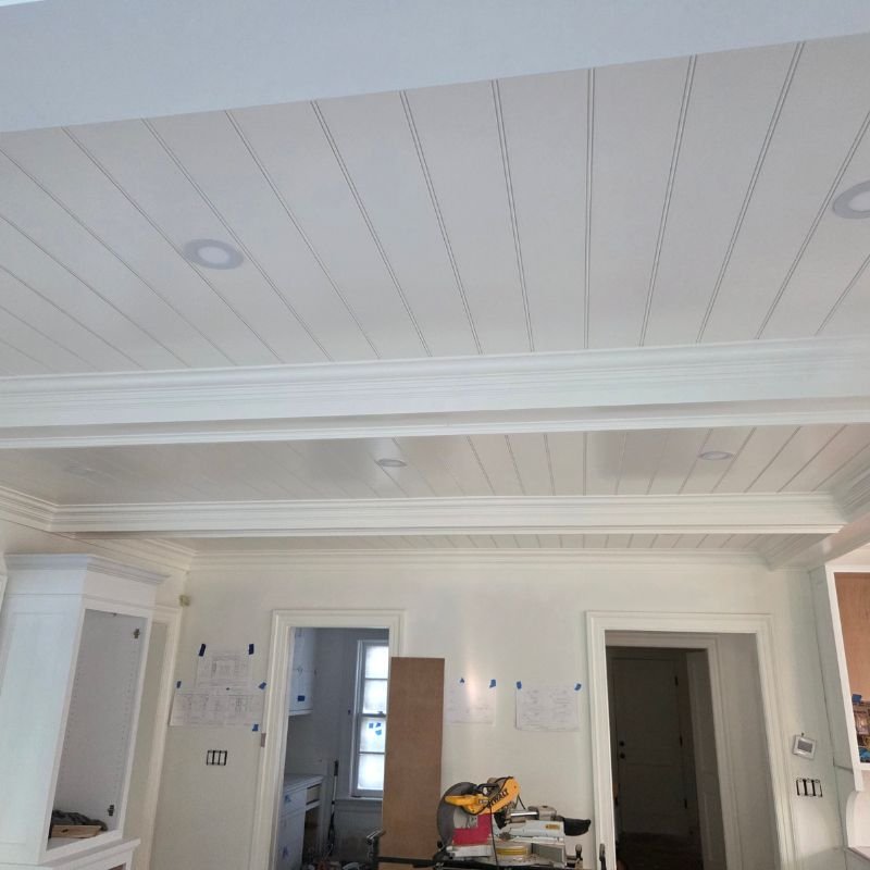 Detailed white crown molding installed in a high-ceiling living room