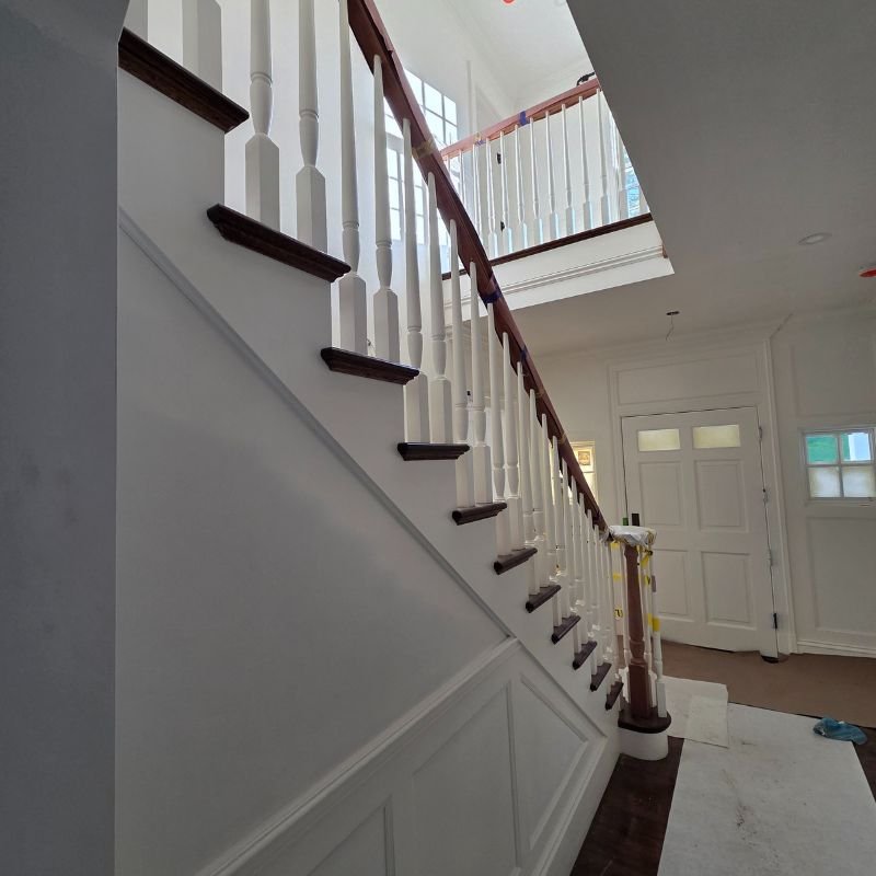 Custom wood staircase with modern black metal railing installed by Innovation Carpentry